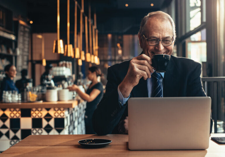 Older man in coffee shop with laptop
