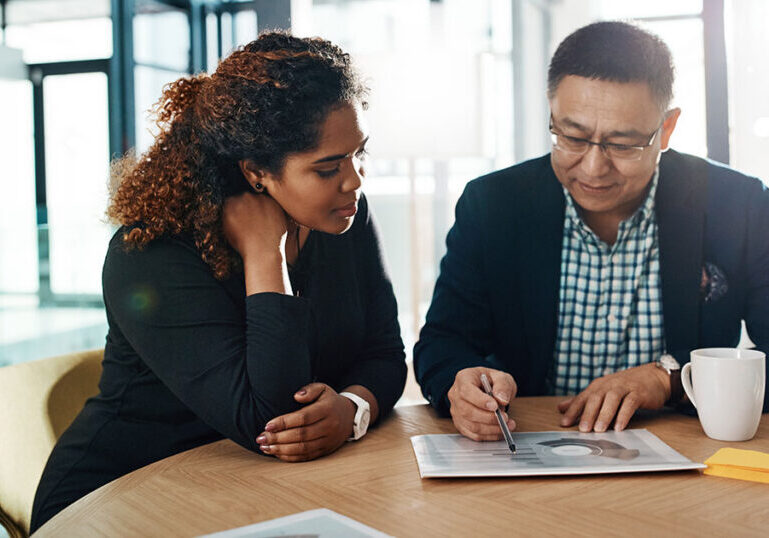 Two professionals reviewing financial documents at a table in a modern office, representing U.S. expats structuring bank accounts and international banking across countries