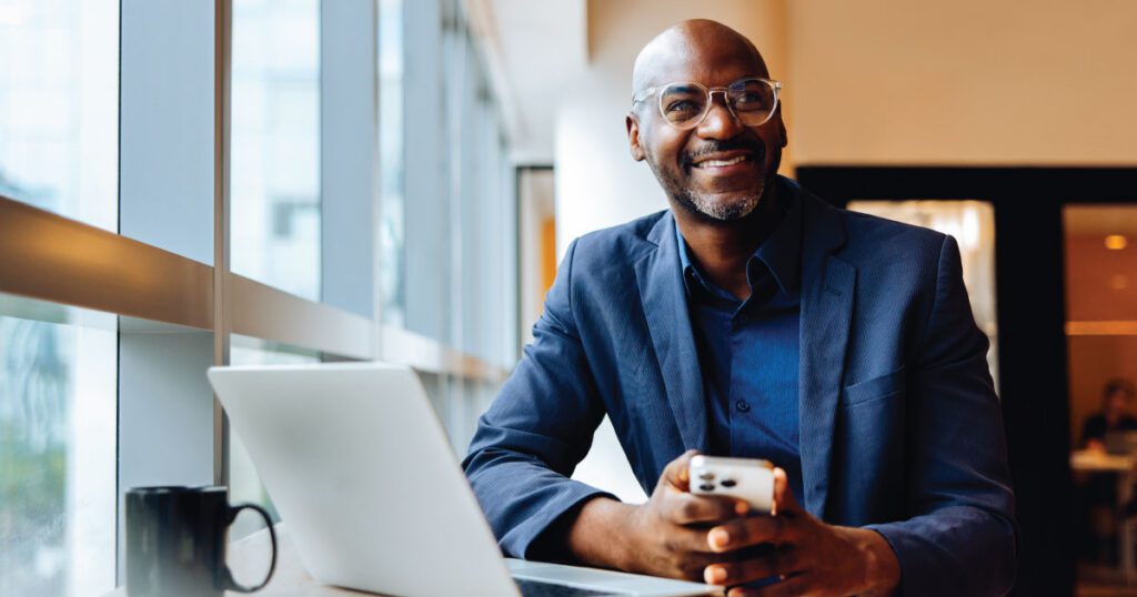 A business professional sitting at a desk with a laptop and phone, representing corporate leadership and board governance protected by D&O liability insurance.