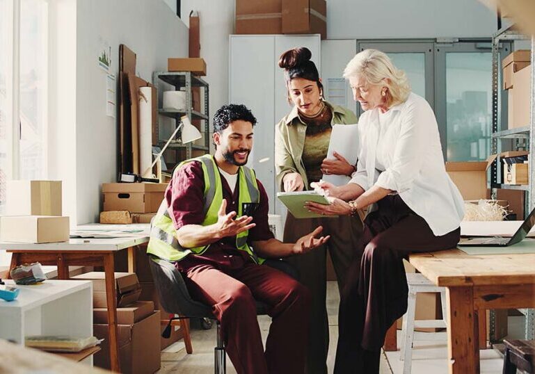 A lean team of small business colleagues reviewing financials and operations together in a warehouse setting as part of a year-end review.